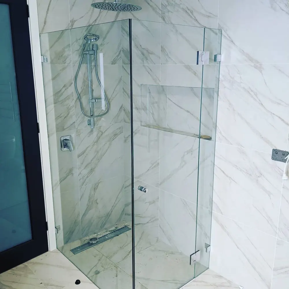 Frameless glass shower screen against marble-look wall panels