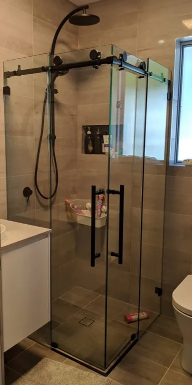 Black-framed sliding glass shower screen over a bathtub
